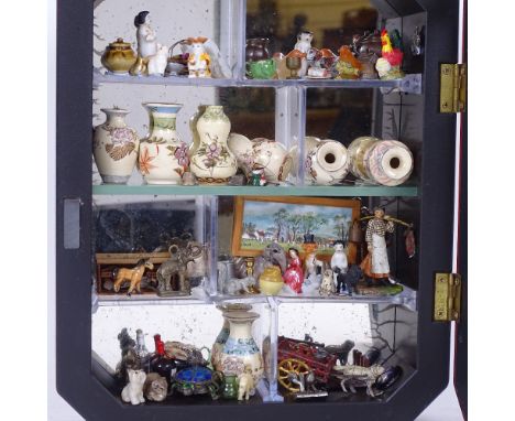 A modern wall-hanging display cabinet, with sectional interior and mirrored back, containing various miniature collectables, 