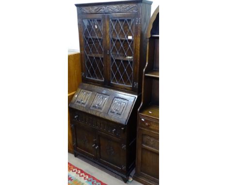 An oak 2-section bureau bookcase with lead-light glazed doors, with a linenfold fall-front, and drawer and cupboards under, W