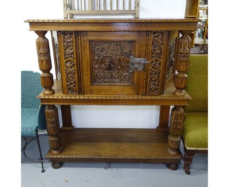 A light oak court cupboard, in 17th century style, with panelled door and allover relief carved decoration, and turned column