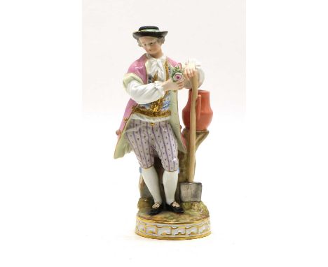 A Meissen porcelain figure, late 19th century, modelled as a gardener leaning on his shovel and an urn beside, underglazed bl