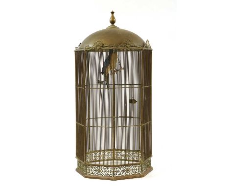 A large brass bird cage, 20th century, the domed top above barred hexagonal body, enclosing model parrot on perch, 76cm wide7