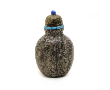 A Chinese crinoid marble snuff bottle,of ovoid form, the domed stopper with a lapis lazuli finial, 8cm highCondition report: 
