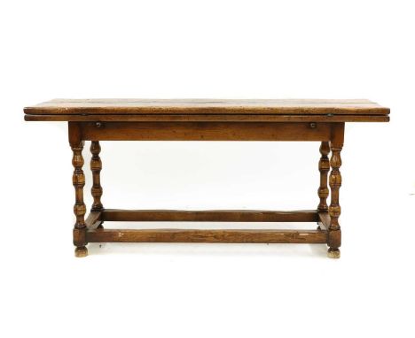 A 17th century-style folding oak dining table, 20th century, the plank top with metal hinges, supported by lopers, raised on 