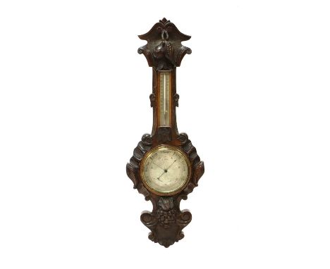 A Victorian oak aneroid barometer, the crisply carved case worked with fruit and scrolls, housing a silvered thermometer and 