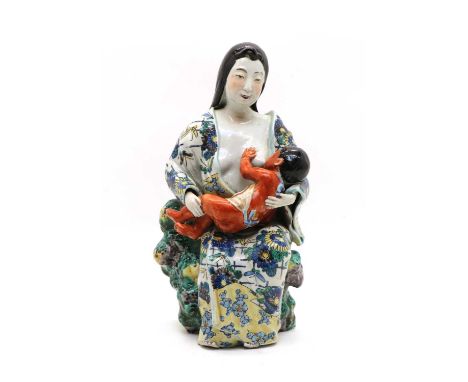 A Japanese Ao-kutani type group, c.1900, of a young mother seated wearing a floral kimono, feeding baby Kintaro in her arms, 