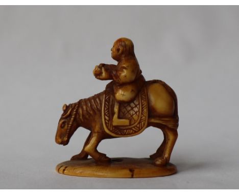 A 19th century Japanese ivory netsuke depicting a man riding a horse reading, on an oval base, signed, 35mm high