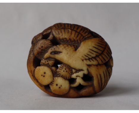 A Japanese carved stag antler manju netsuke in the form of an eagle amongst flower heads, 40mm high 