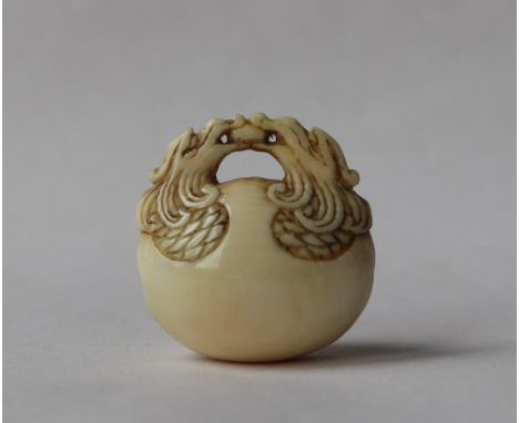 A 19th century Japanese ivory netsuke in the form of a temple bell, the handle formed from two dragons heads, 24mm high 