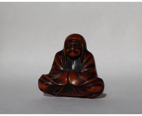 A 19th century carved wooden netsuke  in the form of Daruma, seated crosslegged, 40mm high