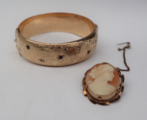 A 9ct yellow gold hinged bangle set with rubies and diamonds in a star formation, approximately 30 grams together with a shel