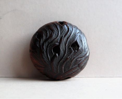 A 19th century Japanese carved wooden Manju netsuke of a stylised bird and feathers, 45mm diameter