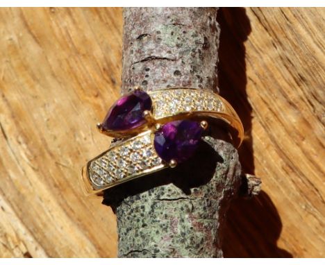 An amethyst and diamond set ring, set with a pair of pear shaped amethysts and round brilliant cut diamonds to the shoulders 