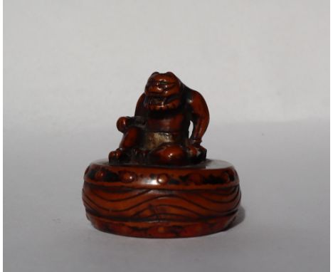 A 19th century Japanese carved wooden netsuke depicting an Oni seated upon a drum, 35mm high 