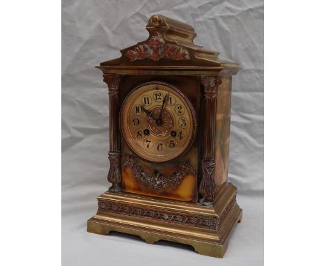 A late 19th century brass mantle clock, with an architectural pediment, mounted with a copper mask and leaves above leaf capp