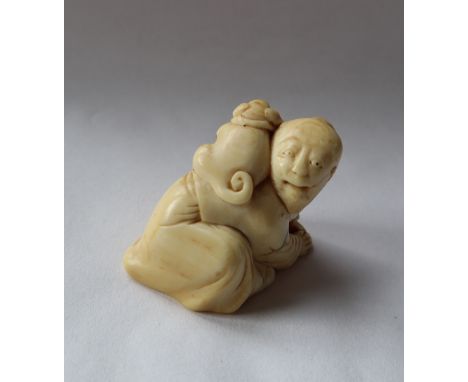 A 19th century Japanese ivory netsuke depicting a man on his hands and knees and a dog on his shoulders, 35mm high