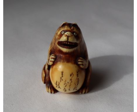 A 19th century Japanese ivory netsuke depicting a bear type figure with a distended stomach with text upon it, 35mm high 