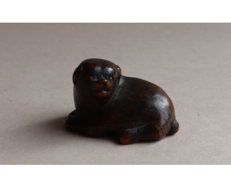 A 19th century Japanese carved wooden netsuke in the form of a recumbent dog, signed, 25mm high