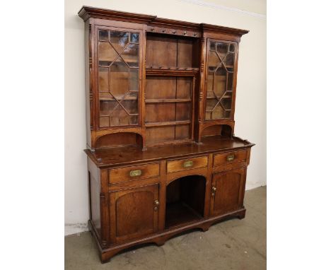 An 18th century and later oak dresser, the inverted breakfront rack with a pair of glazed doors with glazing bars, the centra