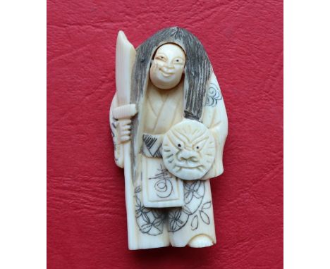 A 19th century Japanese ivory netsuke depicting a standing figure with rotating head holding a mask shield and spear, signed 