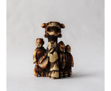 A 19th century Japanese ivory netsuke depicting four boys playing music around a pillar with a boy in a dog of foo mask, sign