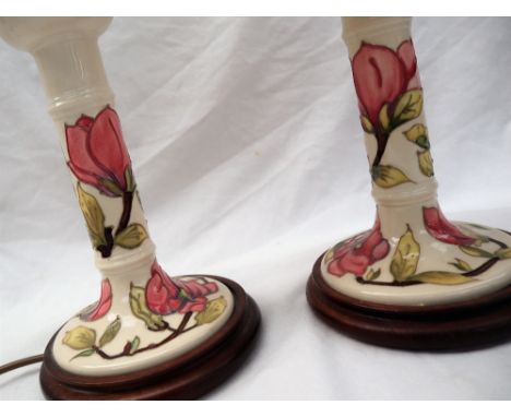 A pair of Moorcroft pottery candlestick table lamps, decorated with pink magnolias to a cream ground 22.5cm high