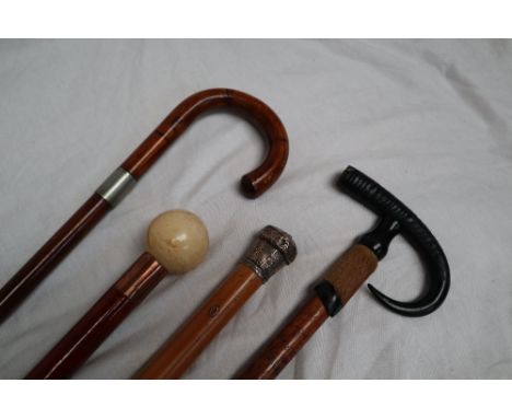 A white metal topped bamboo walking stick together with an antler handled walking stick, and two other walking sticks