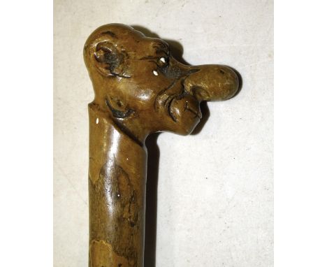 A novelty wooden walking stick with carved caricature head, various smoking pipes and other wooden items. 