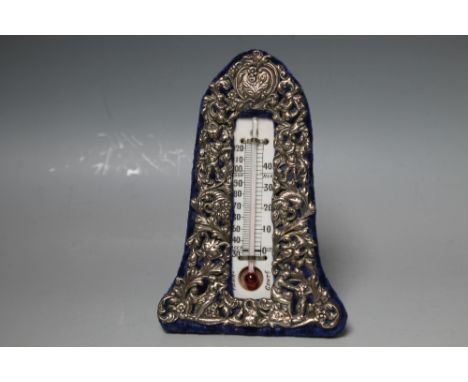 A WILLIAM COMYNS HALLMARKED SILVER EASEL BACKED DESK THERMOMETER - LONDON 1907, having typical Comyns pierced cherubic decora