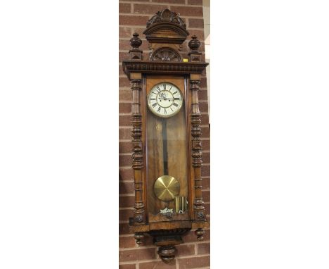 AN EARLY 20TH CENTURY WALNUT CASED LARGE VIENNA WALL CLOCK, with enamel dial, the case with half turned columns, twin brass w