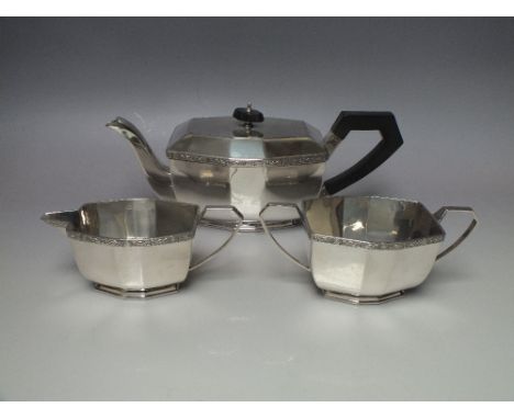 A HALLMARKED SILVER THREE PIECE TEA SERVICE - SHEFFIELD 1937, having an Art  Deco style panel form with an ornate banding to 