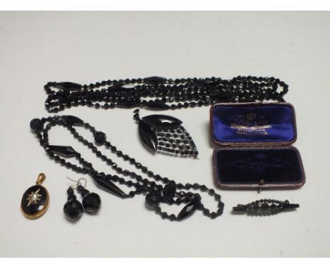 FOUR ITEMS OF VINTAGE JET COSTUME JEWELLERY, comprising two brooches and two carved bead necklaces, together with a pair of m