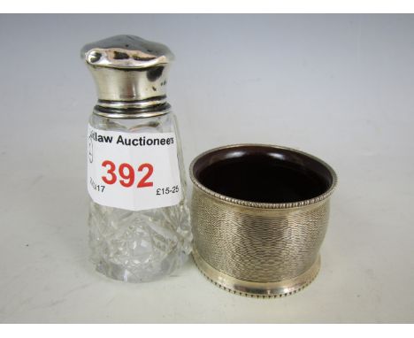 A silver topped perfume bottle together with an engine turned silver and Bakelite lined napkin ring with vacant cartouche