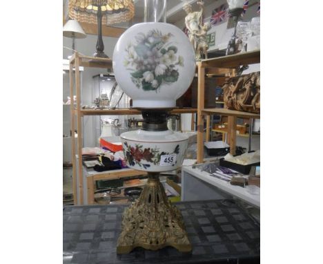 A Victorian oil lamp on cast iron base with hand painted glass font and shade.