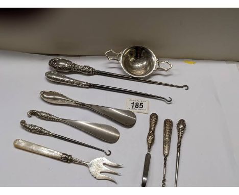 A mixed lot of shoe horns, button hooks etc., some with silver handles, and a plated tea strainer.