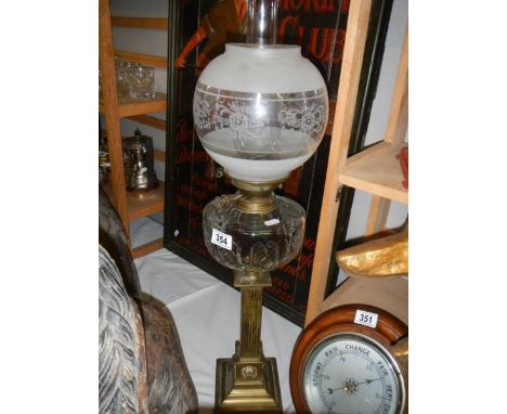 A Victorian oil lamp with brass column, glass font and later shade.