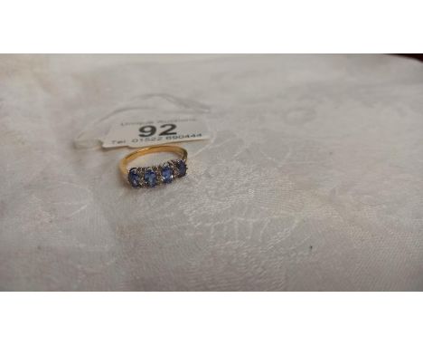 Four oval tanzanites interspaced with three rows of diamonds in 18ct gold ring, size P half, 3.7 grams.