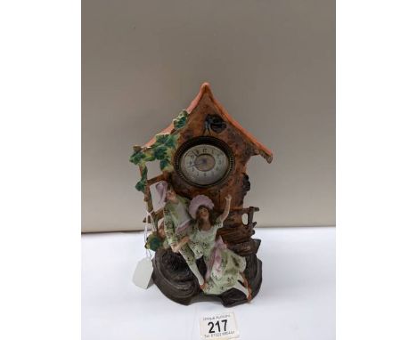 A bisque porcelain mantel clock featuring a boy and girl.