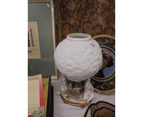 A 20th century porcelain table lamp featuring cherubs with a milk glass embossed shade.