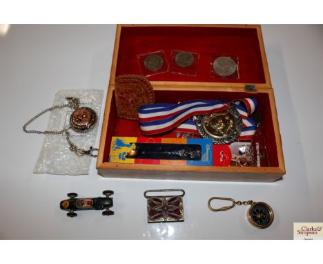 A wooden box containing a toy car, medallions etc.