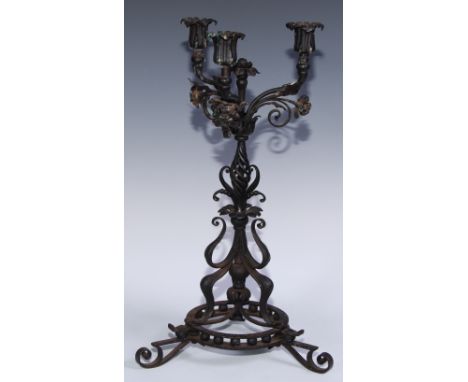 An Arts and Crafts wrought iron three light candelabra, worked in the Art Nouveau taste with flowers on scrolling whiplash st