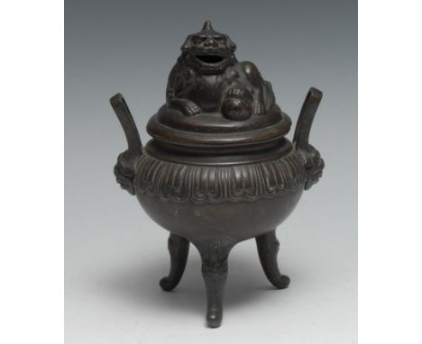 A Chinese bronze tripod censer and cover, surmounted by a temple lion, lappet border, loop handles terminating in masks, outs