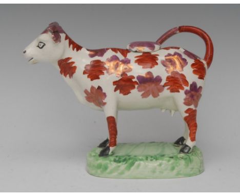 A Swansea cow creamer and cover, probably Cambrian Pottery, with pink-lustre and iron-red markings, green shaped oval base, c