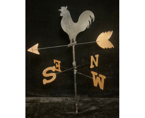 A painted steel weather vane, crested in silhouette by a cockerel crowing at dawn 