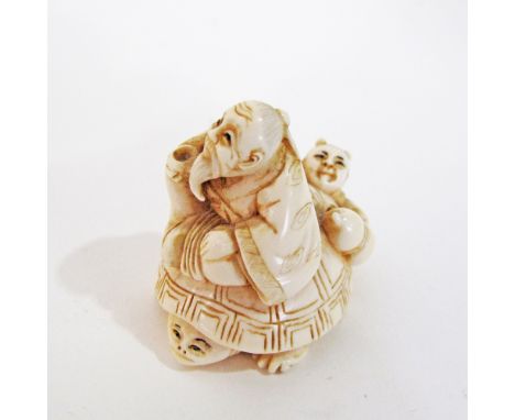 A c19th century Japanese carved ivory netsuke depicting an old man riding a turtle with a child at his back, H4cm, weight 29g