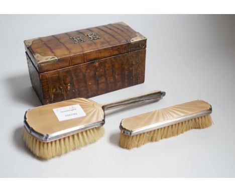 A late Victorian silver mounted crocodile skin jewellery box, 19cm and two silver and enamel mounted brushes.