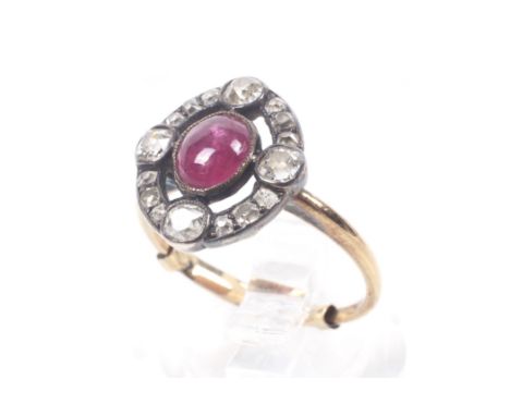 An Edwardian gold, cabochon ruby and old-cut diamond oval cluster ring. Millegrain set at the centre with an oval cabochon ru