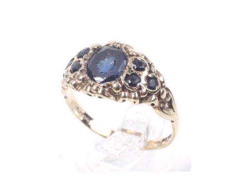 A vintage 9ct gold and very dark blue sapphire-coloured-stone dress ring. Centred with an oval mixed-cut stone between smalle