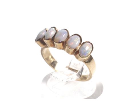 A vintage gold and opal five stone ring. The oval cabochon white opals each rub-over set on a flat-section shank stamped '9ct