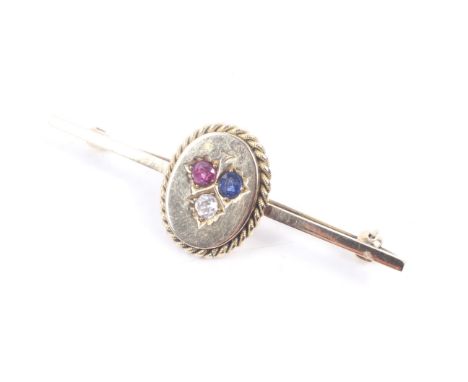 A late Victorian gold, ruby, sapphire and diamond three stone oval panel later applied to a bar brooch. Unmarked, the panel 1