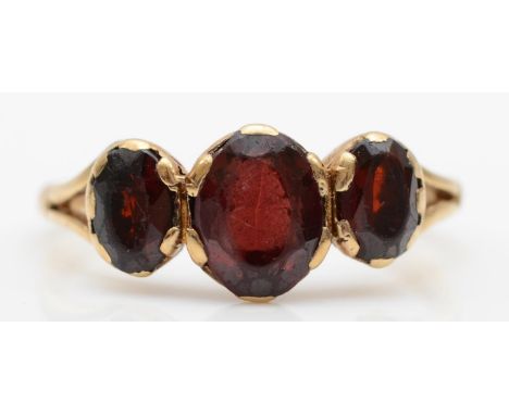 A 9ct gold three stone garnet ring, size P, 2.7gm. 